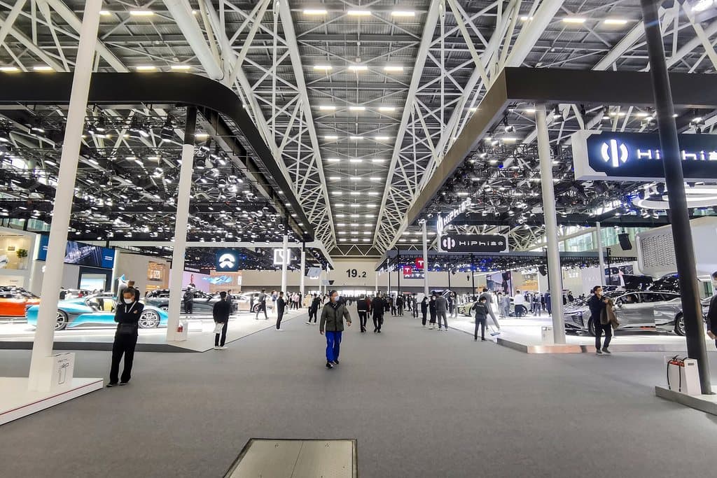 Inside a hall in Zone D of the Canton Fair Complex: cars on show under a steel roof, visitors walking the aisle